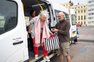 Man-helping-older-woman-out-of-minibus-Cropped-720x480